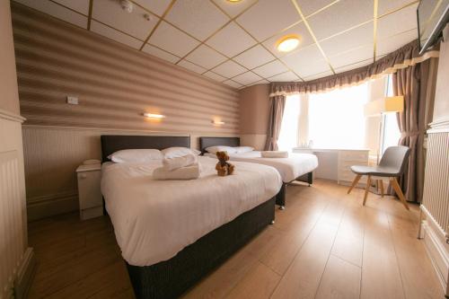 two beds in a hotel room with a teddy bear sitting on them at Lyndene Hotel in Blackpool