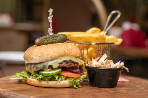 a sandwich with a pickle and a basket of french fries at Lyndene Hotel in Blackpool