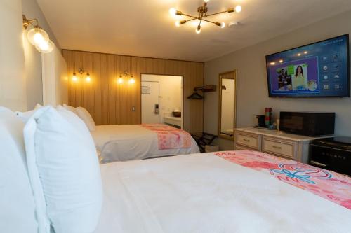 ein Hotelzimmer mit 2 Betten und einem TV in der Unterkunft Dragonfly Inn & Suites in Hastings