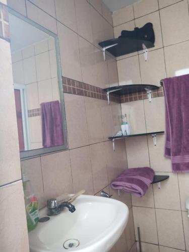 ein Badezimmer mit einem Waschbecken, einem Spiegel und lila Handtüchern in der Unterkunft Hermosa casa Villa de la Abuela en Tampico in Tampico