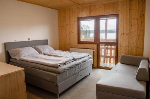 ein Schlafzimmer mit einem Bett und einem großen Fenster in der Unterkunft KROK in Horní Planá