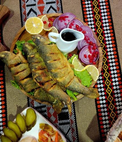 a plate of food with fish and vegetables on a table at Qusar Qala Hotel in Qusar