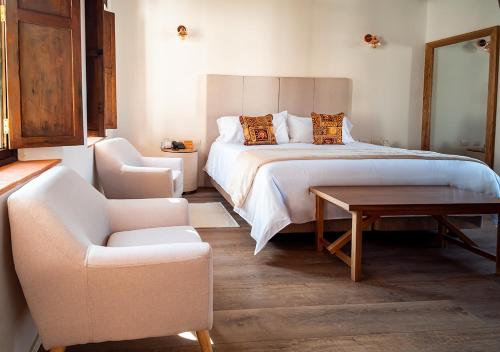 a bedroom with a bed and a chair and a table at Hotel Casa Alcestre in Villa de Leyva