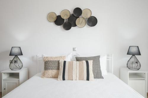 a white bedroom with a white bed with two lamps at Maison Kalogiannis in Patitiri