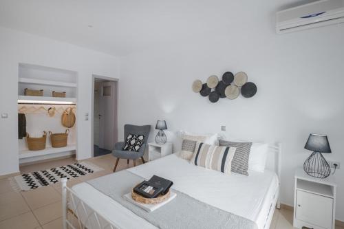 a white room with a bed and a chair at Maison Kalogiannis in Patitiri