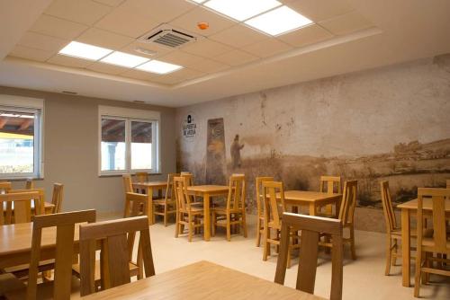 una habitación con mesas y sillas y un cuadro en la pared en LA PUERTA DE ARZÚA, en Arzúa