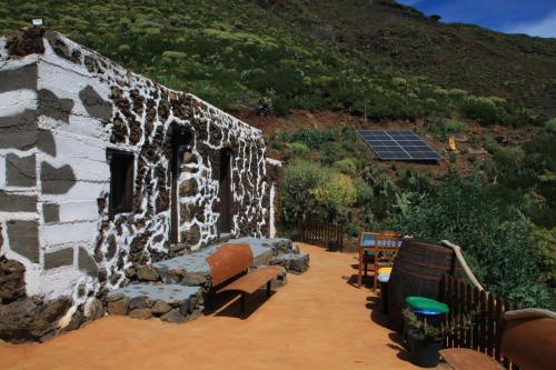 un ancien bâtiment en pierre avec des bancs et un panneau solaire dans l'établissement La Chusmita, à Valverde