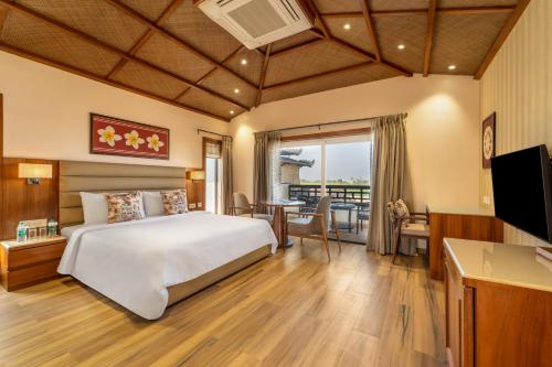 a bedroom with a bed and a desk and a television at Shyama Sarovar Portico in Orai
