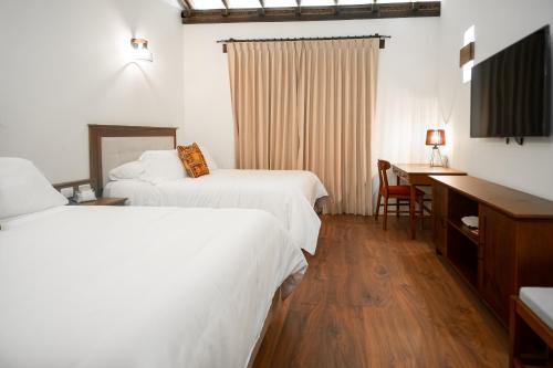 a hotel room with two beds and a desk at Hotel Casa Alcestre in Villa de Leyva