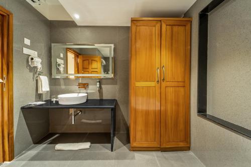 a bathroom with a sink and a wooden cabinet at Shyama Sarovar Portico in Orai