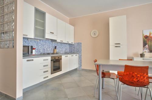 a kitchen with white cabinets and a table and chairs at Terraces d'Orlando - Family Apartments with Sea View and Pool in Capo dʼOrlando