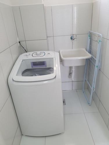 ein kleines Bad mit einer Waschmaschine und einem Waschbecken in der Unterkunft Apt próx. Shopping Pantanal/Centro Político in Cuiabá