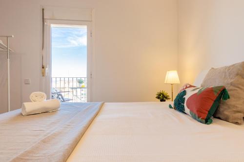 a white bedroom with a large bed with a window at WOOOW!!! Àtic Cèntric amb Terrassa in Tarragona