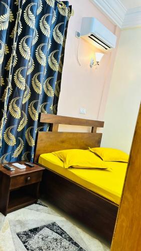 a bedroom with a bed with yellow sheets and a curtain at Chambre meublée Biyem Assi TKC in Yaoundé