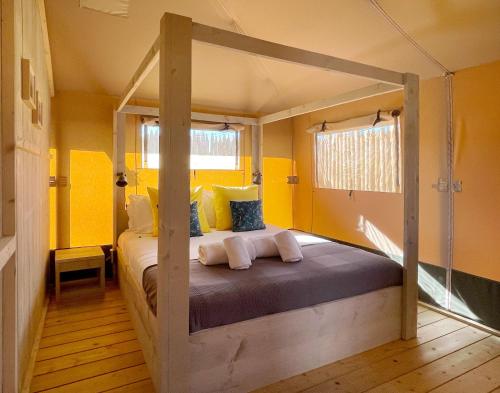 a bedroom with a canopy bed with yellow walls at Kuanza Farmhouse and Lodge in Zambujeira do Mar