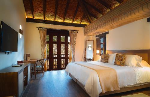 - une chambre avec un grand lit, un bureau et une télévision dans l'établissement Hotel Casa Alcestre, à Villa de Leyva