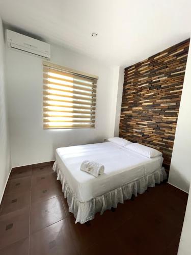 1 dormitorio con 1 cama blanca grande y pared de ladrillo en CASA VACACIONAL TANiA en Salinas