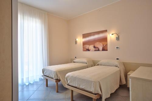 two beds in a room with a painting on the wall at Terraces d'Orlando - Family Apartments with Sea View and Pool in Capo dʼOrlando