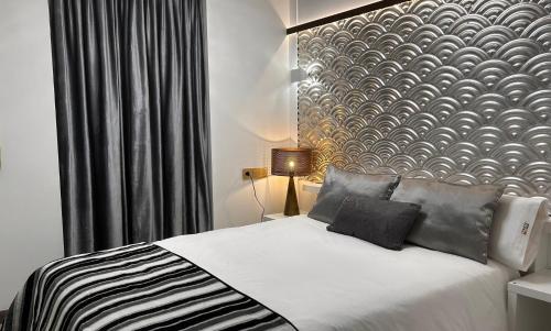 a bedroom with a white bed with a patterned wall at HOTEL FUENTE REDONDA LUXURY in Úbeda