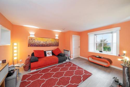 uma sala de estar com um sofá vermelho e uma janela em Blindwelleyes Cottage em Blairgowrie