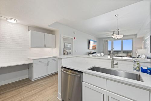 eine Küche mit weißen Schränken und einer Spüle aus Edelstahl in der Unterkunft Modern Beach Vibe with a Breathtaking View - Stunning Pool - Pier Park in Panama City Beach