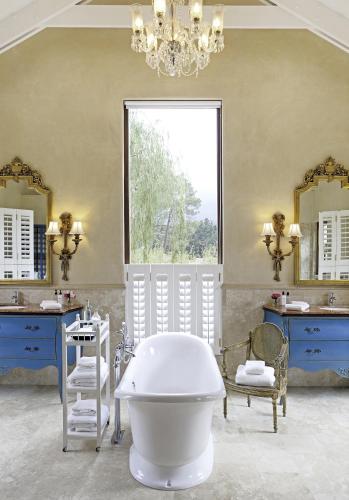 a bathroom with a tub and two sinks and a large window at La Residence in Franschhoek