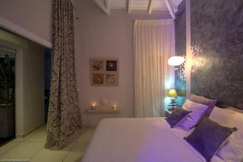 a bedroom with a large bed with purple pillows at Villa Estheria in Sainte-Anne