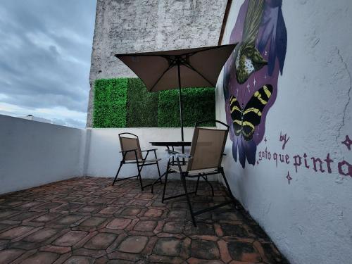 a table with chairs and an umbrella next to a wall at Casa El Colibrí CEC in Tehuacán