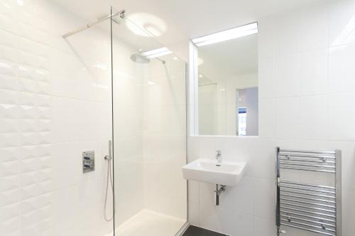 baño blanco con ducha y lavamanos en Destiny Scotland -The Malt House Apartments, en Edimburgo