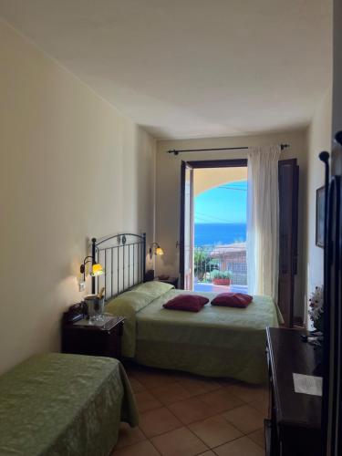 a bedroom with two beds and a large window at Kalura B&B in San Vito lo Capo