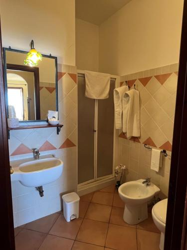 Un baño con lavabo, inodoro y espejo. en Kalura B&B, en Macari