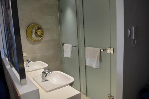 uma casa de banho com 2 lavatórios e um chuveiro com um espelho. em Luxxe interior design condo @ Novotel Suites Manila - Acqua em Manila