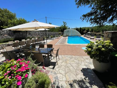 a patio with a table and an umbrella and a pool at Vila Jovanovic in Barajevo