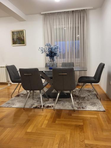 a dining room table with chairs and a vase of flowers at URBAN GREY APARTMAN in Sremska Mitrovica