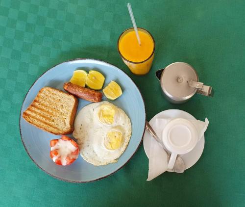 een blauwe plaat met eieren en toast en een kop sinaasappelsap bij Modern Cozy Studio House in Diani Beach