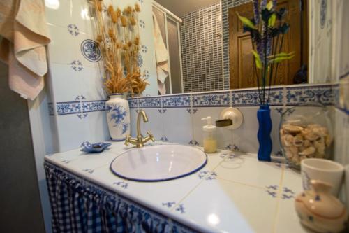 baño con lavabo con azulejos azules y blancos en El Refugio de la Esquina, en Mata de Quintanar