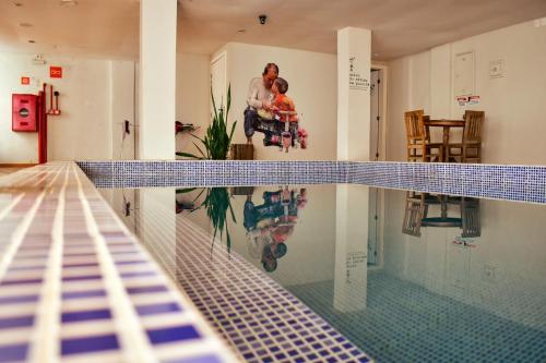 a swimming pool with a reflection of a family in the water at Hostel Poesia in Foz do Iguaçu