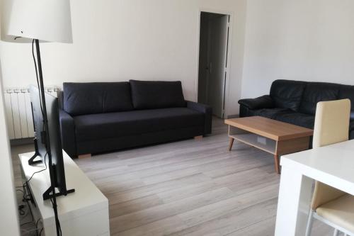 un salon avec un canapé noir et une table dans l'établissement 65m with small balcony - near naval base, à Toulon