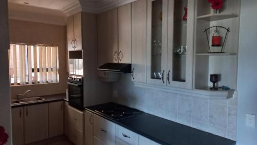 a kitchen with white cabinets and a black counter top at 8 On Eagle Self Catering Apartment in Umtentweni