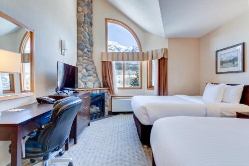 a hotel room with two beds and a desk at Chateau Canmore in Canmore