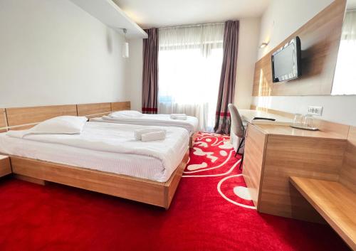 ein Schlafzimmer mit einem großen Bett und einem roten Teppich in der Unterkunft Hotel Ave Lux in Braşov