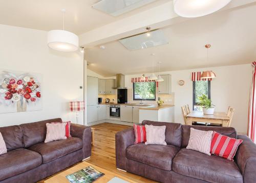 a living room with two brown couches and a kitchen at Cedar Retreats in Masham
