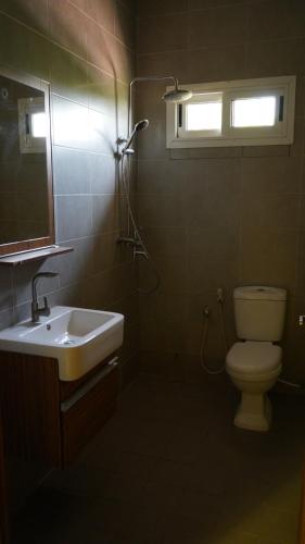 a bathroom with a sink and a toilet and a window at Maajob Resort in Brikama