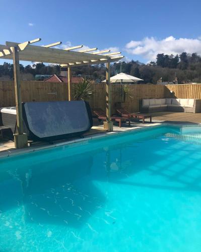 a swimming pool with a pergola and blue water at The Purple Tree Guest House in Torquay
