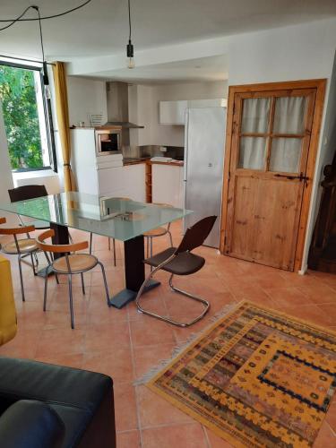 une cuisine avec une table en verre et des chaises dans une pièce dans l'établissement GITE AU ROC DE BOURZAC AVEC PISCINE PRIVÉE, à Bayac