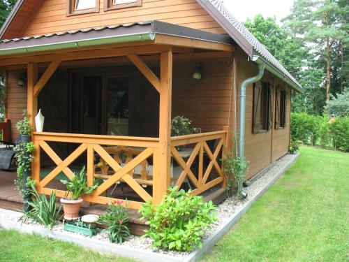 a wooden cabin with a porch and a fence at Wilkaski zakątek in Giżycko