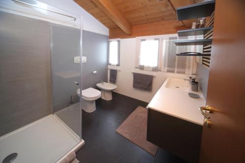 een badkamer met 2 toiletten, een douche en een wastafel bij Dosse House in Caponago