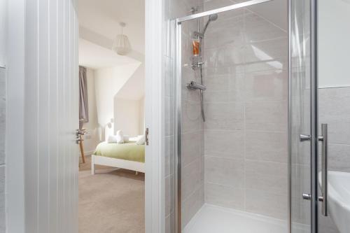 a bathroom with a walk in shower next to a bed at Endymion in Porthtowan