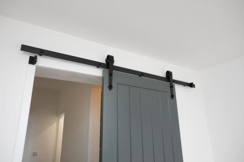 a sliding garage door on a white wall at Cudworth House, Barnsley for contractors & Families, off-road parking, speedy WIFI,etc in Barnsley