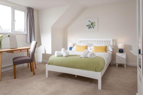 a white bedroom with a bed and a desk and a desk at Endymion in Porthtowan